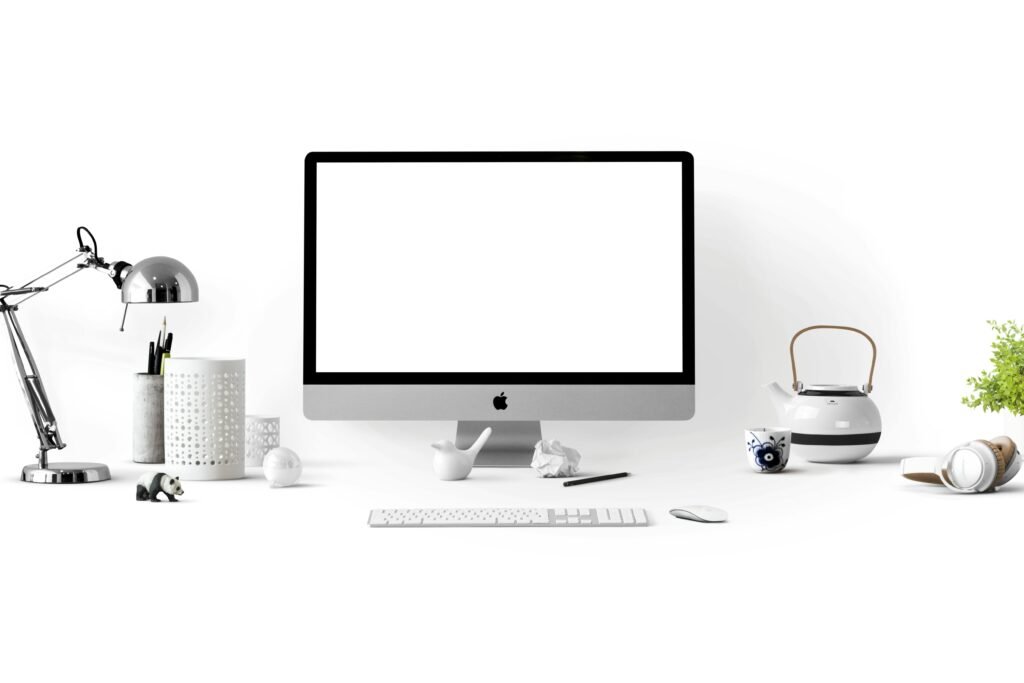 Minimalist office desk with an iMac, lamp, and stationary, perfect for tech backgrounds.